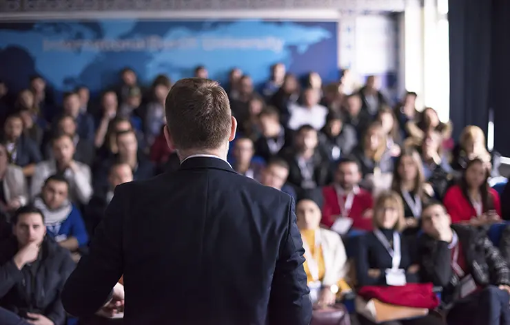 Homem palestrando para um grupo de pessoas em um evento corporativo