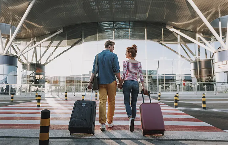 Casal de mãos dadas com malas no aeroporto